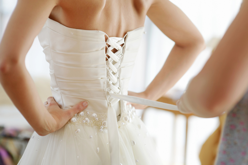 Gros plan sur le laçage au dos d’une robe de mariée, ajustement final avant la cérémonie