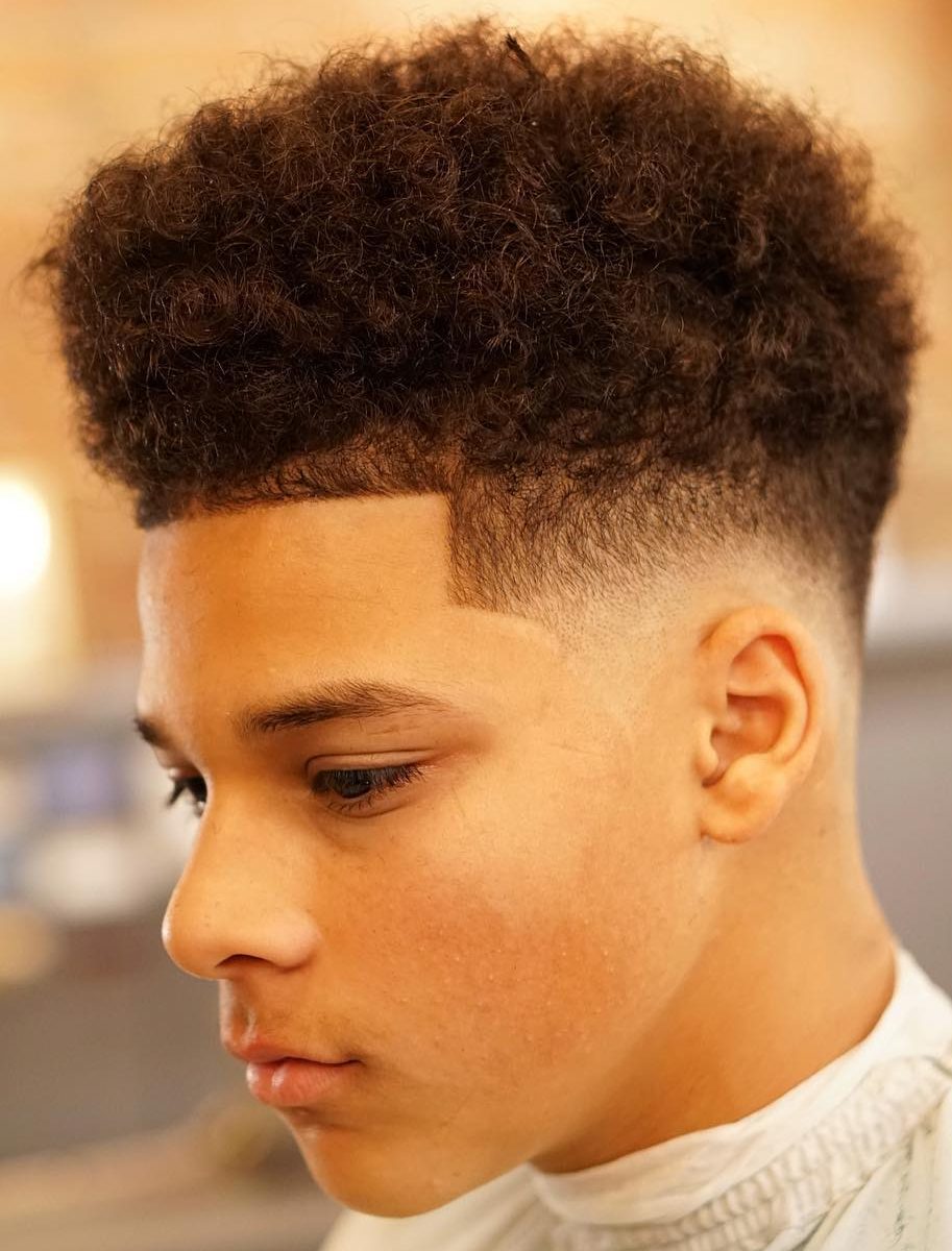 Low bald fade with medium to long curls on top, clean shape up in front and on the sides