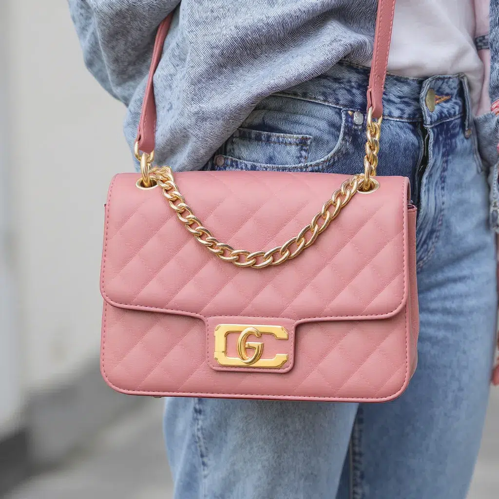 Sac matelassé rose à chaîne dorée porté en bandoulière, accessoire élégant pour rehausser une tenue automnale.