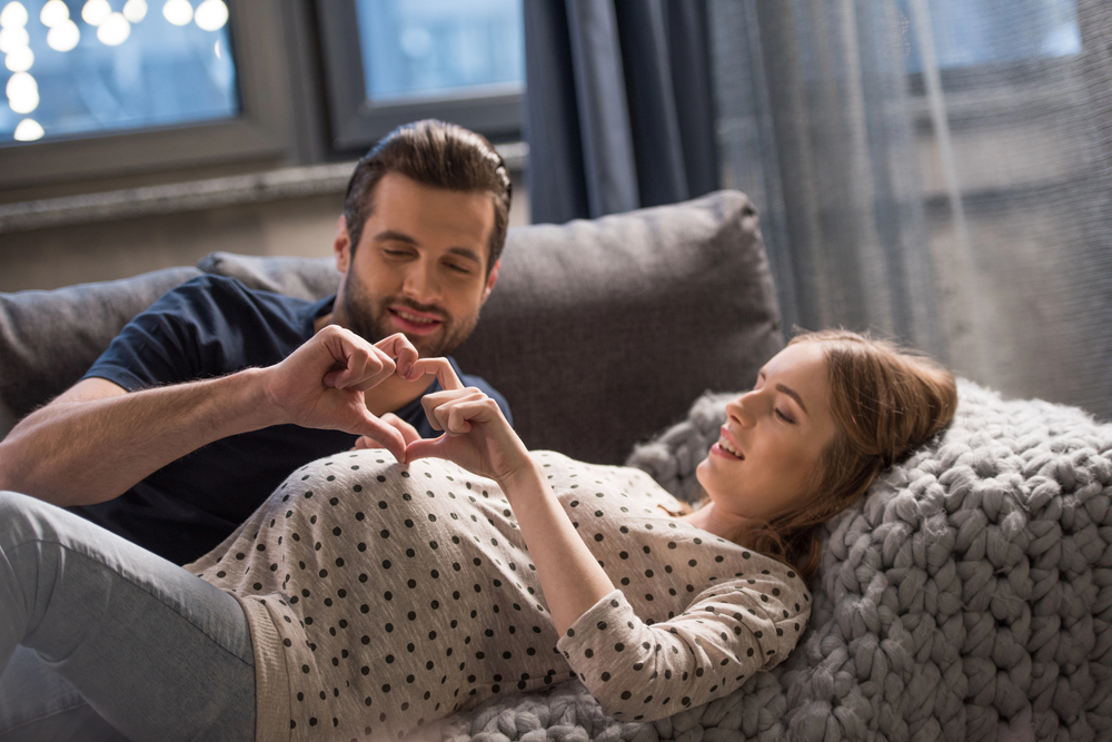 Femme enceinte allongée avec son partenaire, moment de complicité prénatale en couple