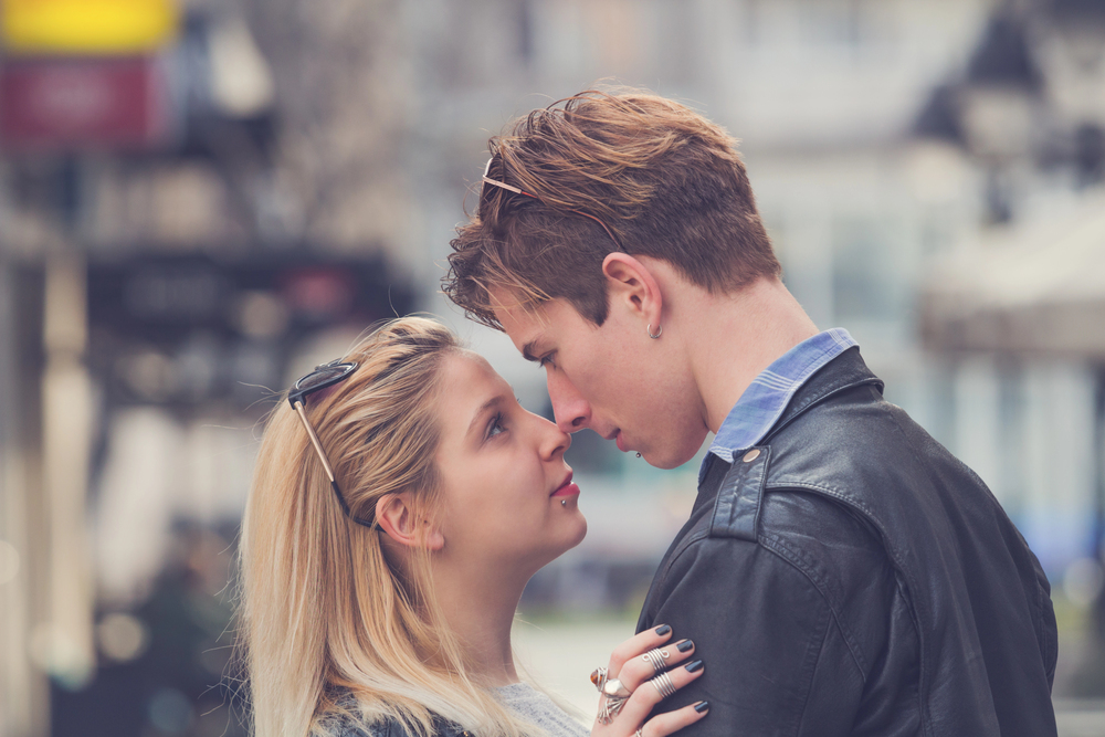 Jeune couple dans la rue très proches, regard intense entre eux, attraction physique irrésistible