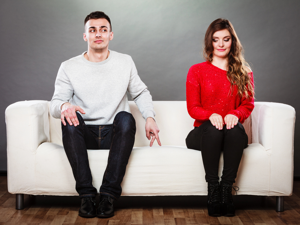 Homme assis raide à côté d’une femme souriante, nervosité visible dans une interaction timide