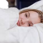 jeune femme couchée dans linge de lit blanc
