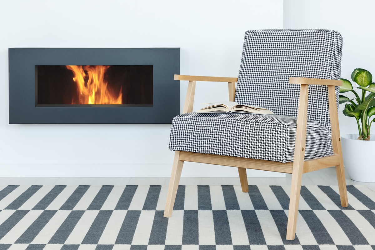 retro armchair with a book next to a fireplace set 2021 08 26 15 45 18 utc1 - Cheminée bio : faut-il choisir ce type de chauffage ?