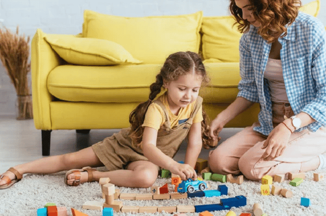  une jeune fille nounou joue avec une petite fille.