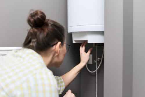 home water heater woman regulates the temperature 2022 01 20 19 53 30 utc 500x333 - Quel type de chauffe-eau choisir selon vos besoins ?