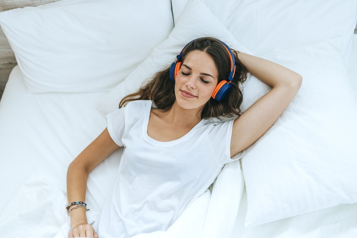 young woman sleeping in bed at home with headphone 2022 03 08 01 25 13 utc - Dormez mieux et réveillez vous en meilleure santé en choisissant le bon oreiller !