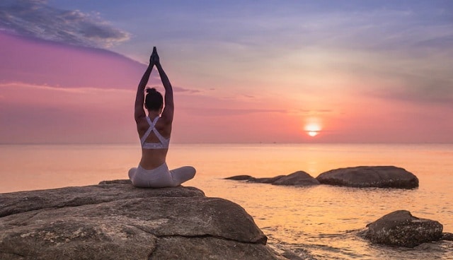 fille pratiquant le yoga au bord de la mer