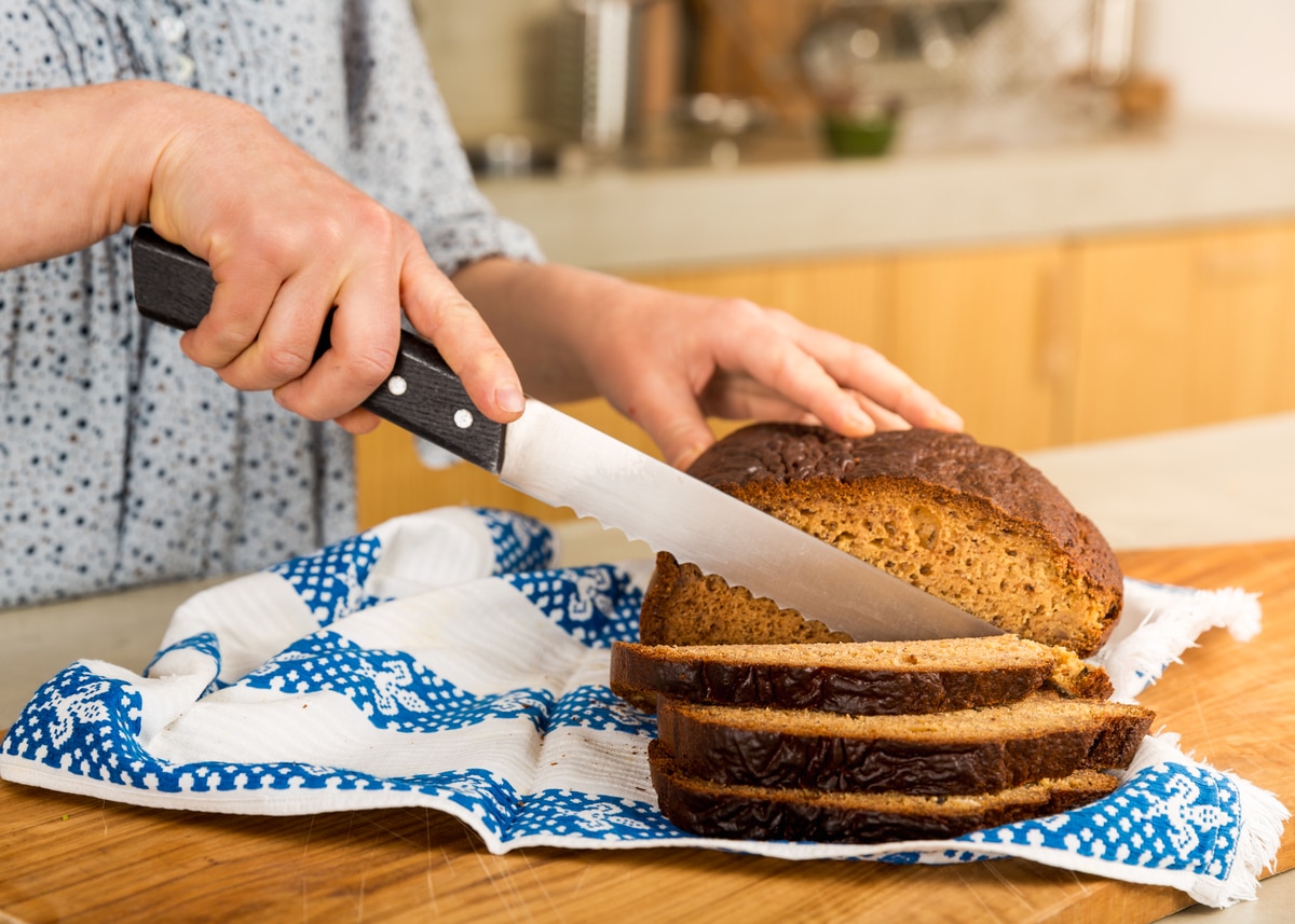 femme qui coupe du pain sans gluten dans sa cuisine