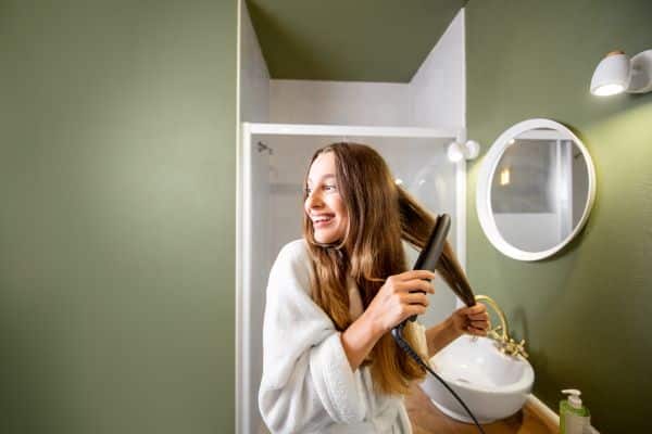 Lissage des cheveux femme dans la salle de bain
