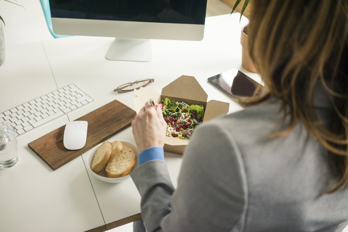 woman eating salad for lunch at her desk 2022 03 08 01 24 06 utc - Comment manger plus équilibré et plus sain au bureau tout en se faisant plaisir ?