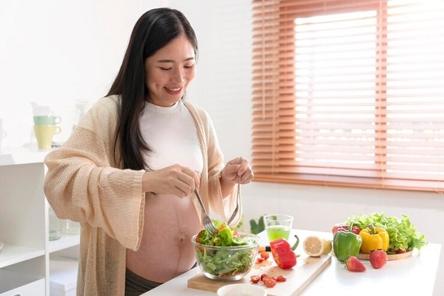 femme enceinte asiatique préparant une cuire de salade à la maison