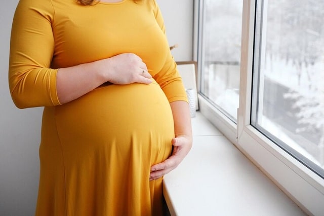 femme enceinte vêtue d'une robe jaune