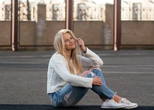 Jeune jolie femme blonde à la mode vêtue d'un jean déchiré et en sneakers