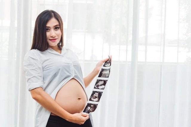 portrait d'une jeune femme enceinte tenant une photo d'échographie