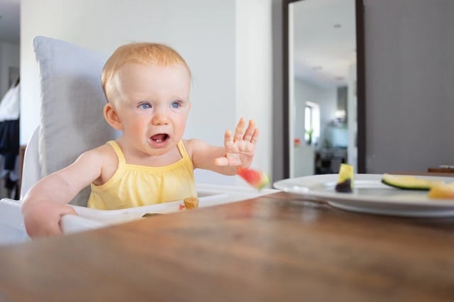 bébé réfusant de manger et jettant une morceau de fruit