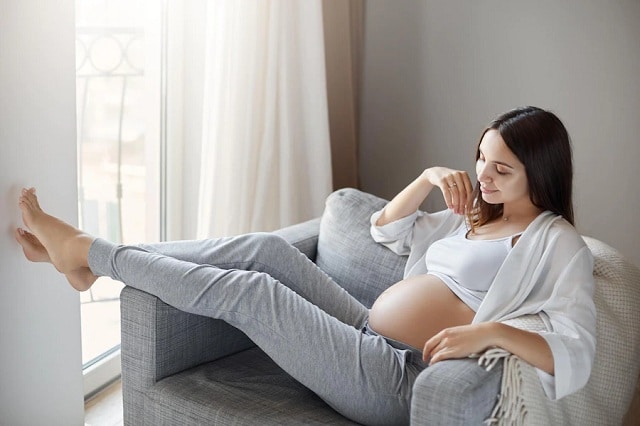femme enceinte se détendre à la maison appliquant des produits cosmetique sur son visage