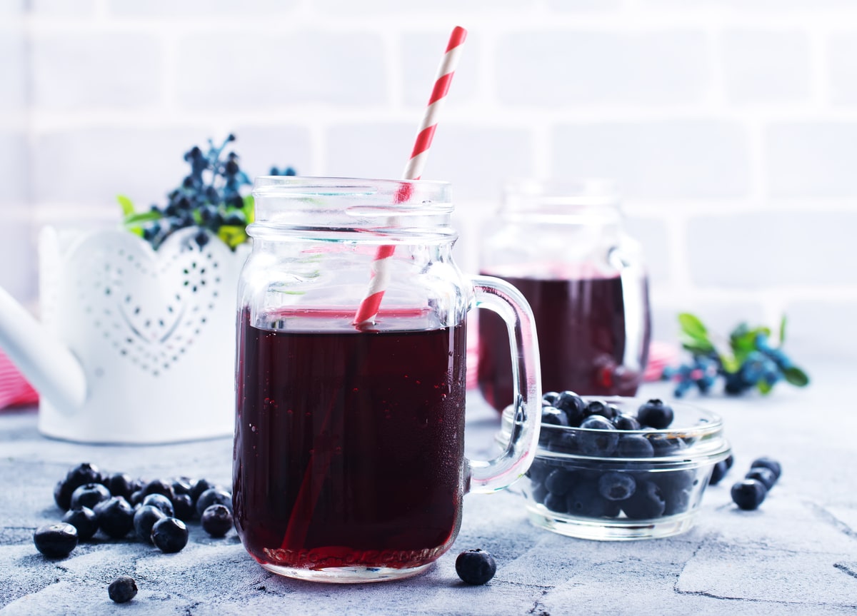 jus de myrtille frais sur une table paille