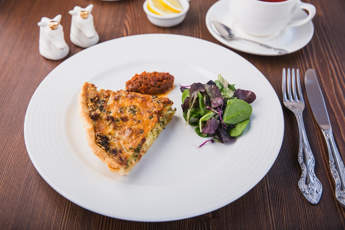 Coupez une délicieuse tarte aux légumes frais sur une assiette blanche, menu du restaurant