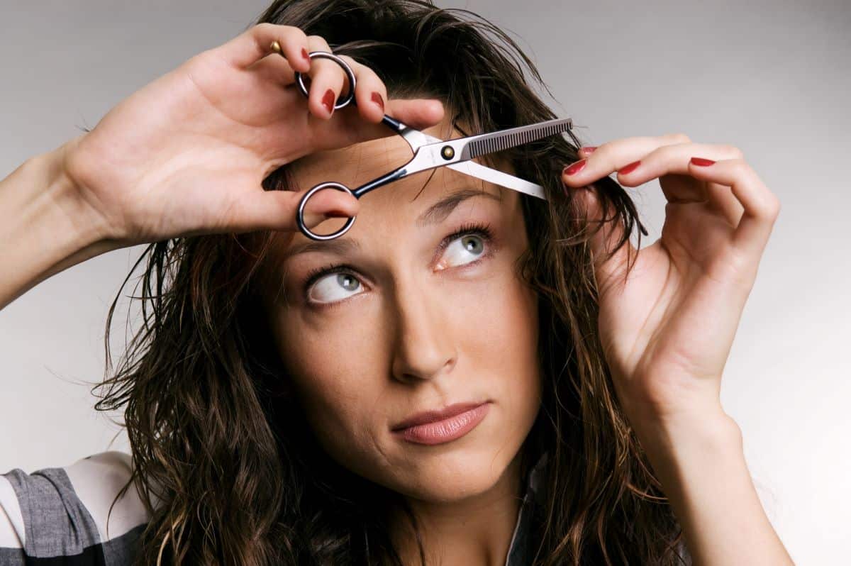 femme coupe sa frange de cheveux