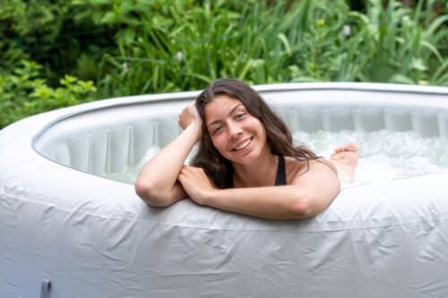 belleadolescente avec de longs cheveux foncés se détend dans une piscine gonflable de jardin avec jacuzzi.