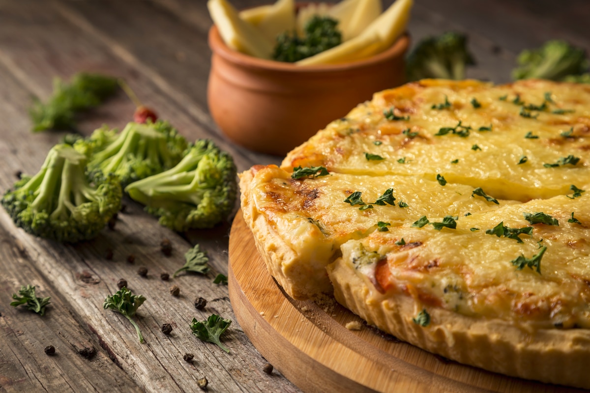 Tarte aux légumes frais servie sur une planche à découper sur une table en bois rustique. Mise au point sélective sur la tarte