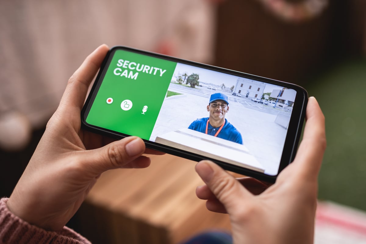 femme regardant livreur à travers le système de caméra de sécurité sur téléphone mobile à la maison concept de mode de vie de technologie intelligente cctv shocker électrique