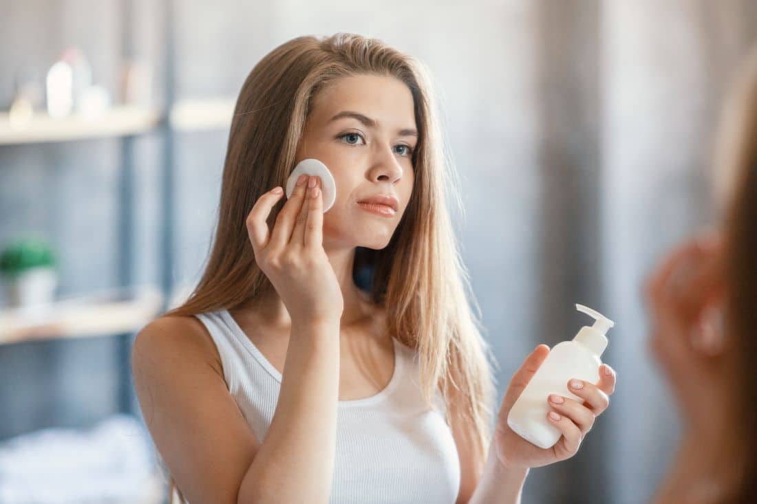 femme qui enlève son maquillage avec un démaquillant