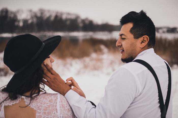 les mariés mexicains en vêtements de mariage et bretelles s'assoient sur la neige en hiver