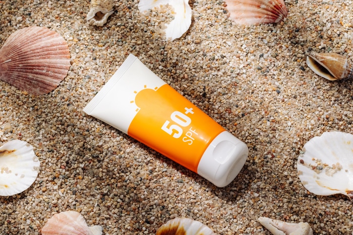 tube orange de crème solaire sur la vue de dessus de la plage de sable