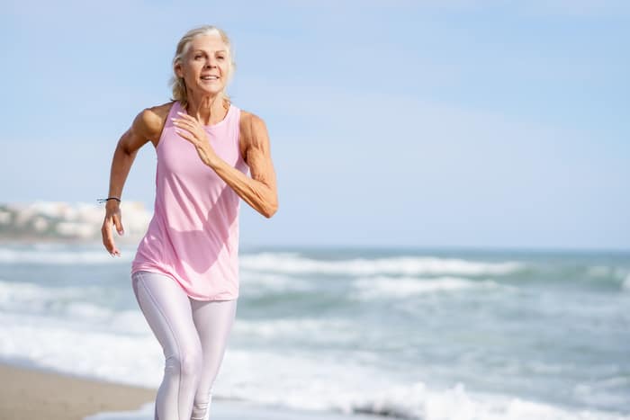 femme mûre courant le long du rivage de la plage. femme plus âgée faisant du sport pour garder la forme