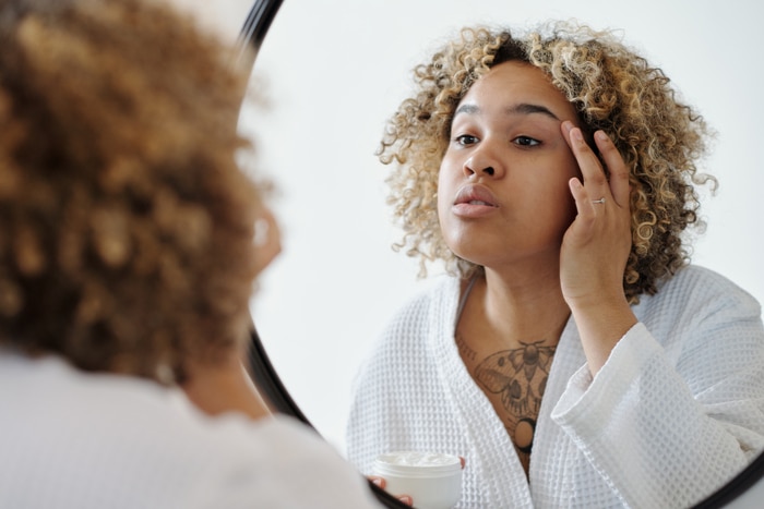 jeune femme afro-américaine appliquant une lotion sur la peau de la paupière eczema