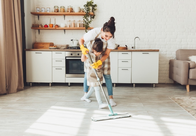 une petite fille et sa mère nettoient la maison, un enfant lave le sol de la cuisine