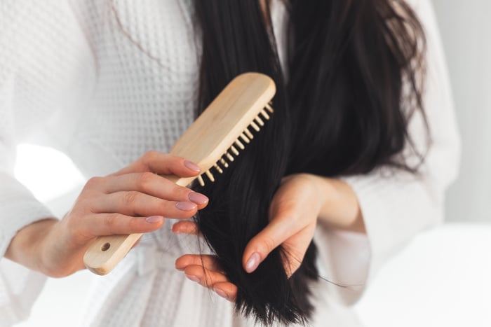 Portrait femme brune en peignoir se brosser les cheveux vue rapprochée