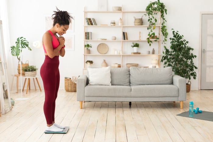 heureuse fille noire se pesant sur des échelles de poids perdre du poids à l'intérieur