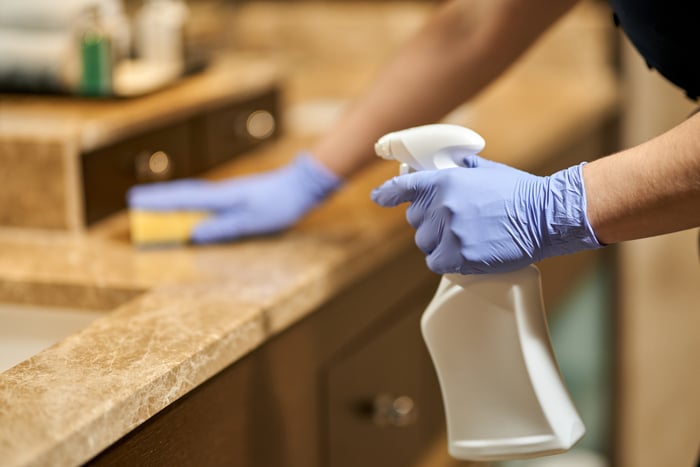 femme de chambre en uniforme pendant le nettoyage de la salle de bain