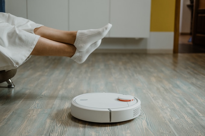 aspirateurs robots, robots laveurs. Maison intelligente. aspirateur robot pendant que la femme se détend sur le canapé. aspirateur robot automatique sur parquet stratifié, technologie de nettoyage intelligente