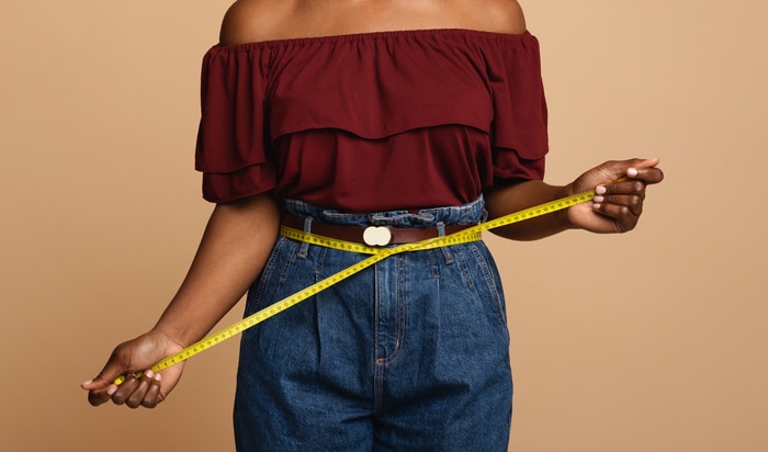 femme mince afro-américaine méconnaissable mesurant sa taille, recadrée