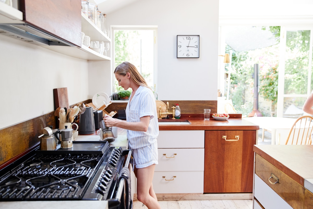 femme portant un pyjama à la maison dans la cuisine faisant du café frais