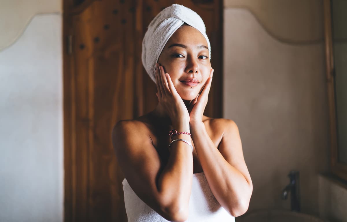 belle femme asiatique serviette tete faisant des soins visages de routine