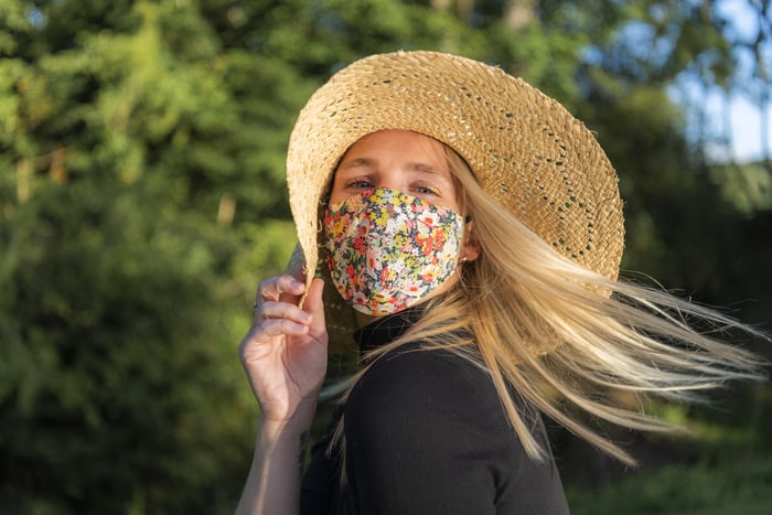 belle jeune femme portant un masque facial de coronavirus recouvert d'un motif floral pendant le covid 19