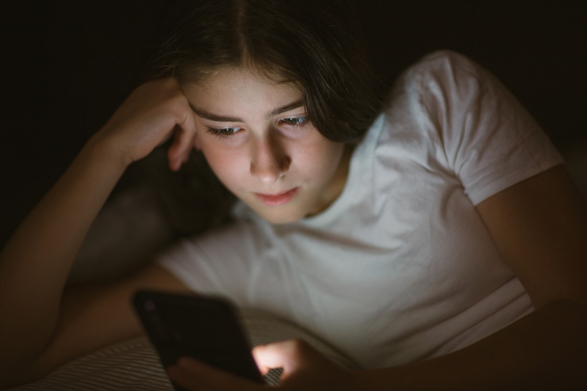 une adolescente est allongée au lit le soir ou la nuit et regarde le téléphone. dépendance mobile.
