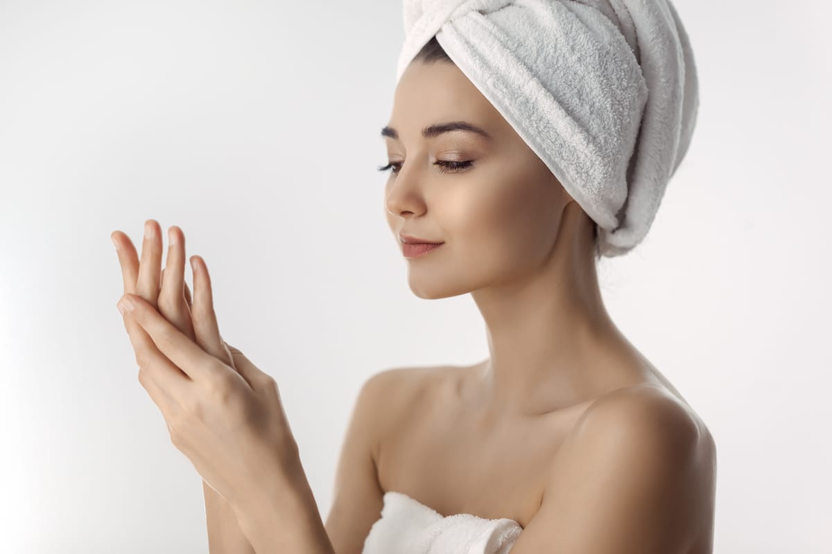 femme brune fraîche et belle appliquant de la crème pour les mains