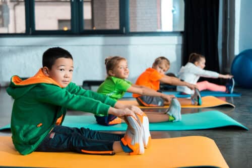 foyer sélectif d'enfants multiethniques s'étirant sur des tapis de fitness dans un centre sportif