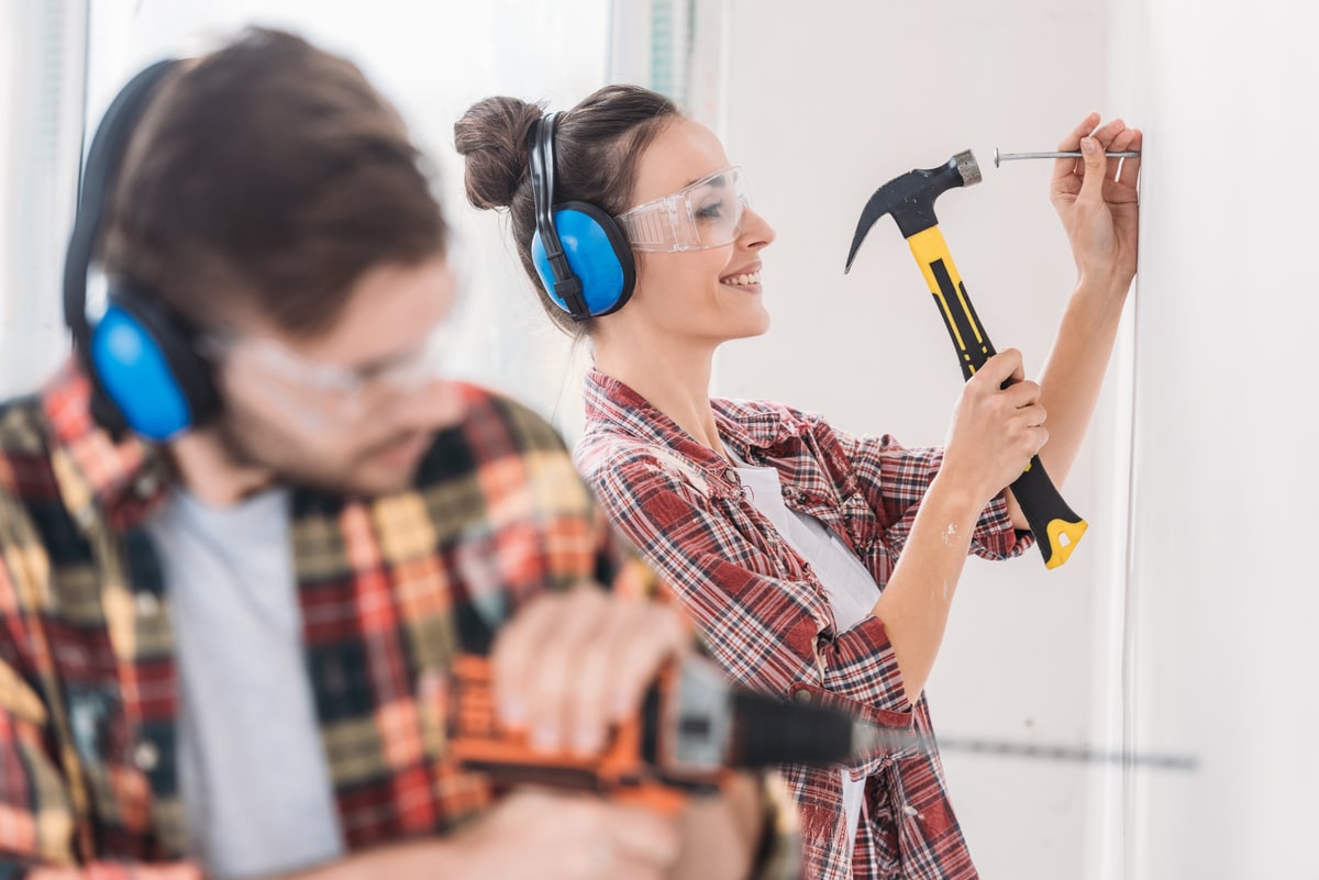 foyer sélectif du jeune couple martelant et forant le mur pendant la rénovation