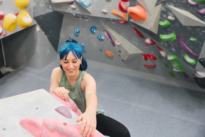 femme souriante atteignant le sommet du mur d'escalade dans un centre d'activités intérieur