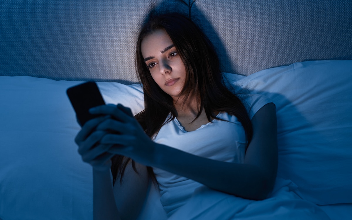 femme utilisant un smartphone au lit la nuit