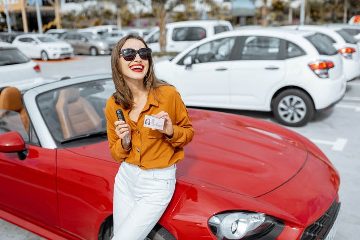 femme avec clés et permis près de la voiture au parking