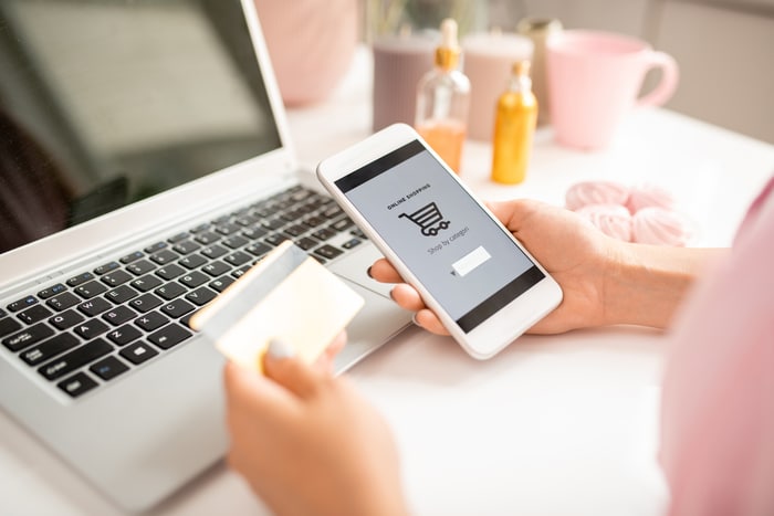 young customer with smartphone searching for goods in online shop