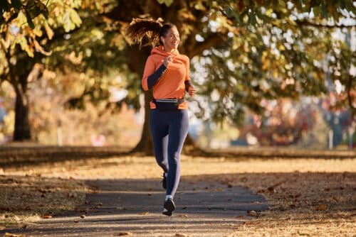jeune sportive heureuse courant dans le parc pendant la journée d'automne.
